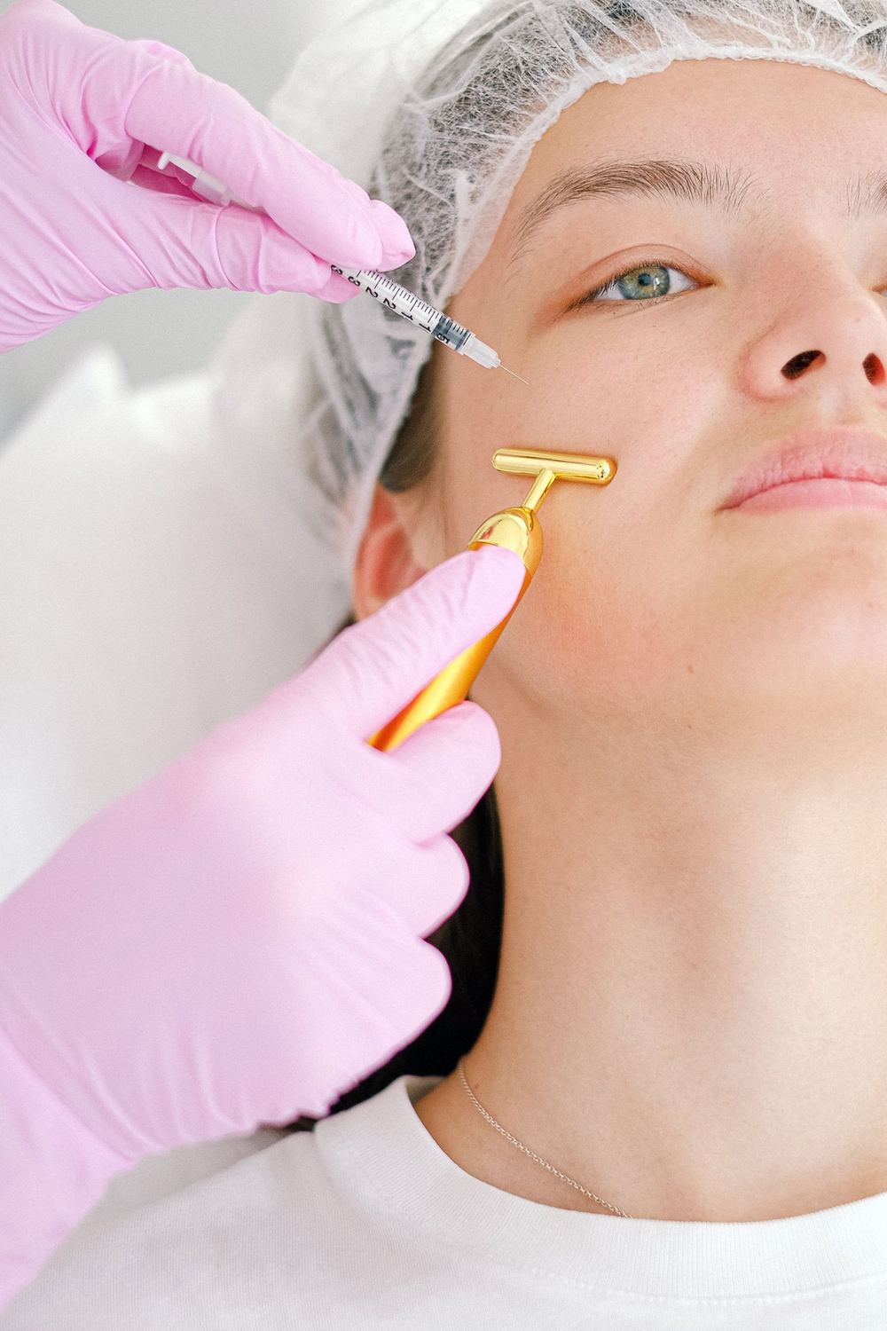 A gloved practitioner performing a precise aesthetic treatment in a clinical setting.