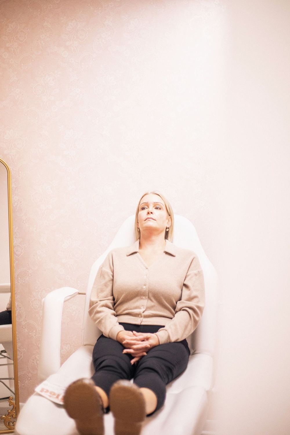 A client resting calmly in a bright, softly toned skincare clinic.